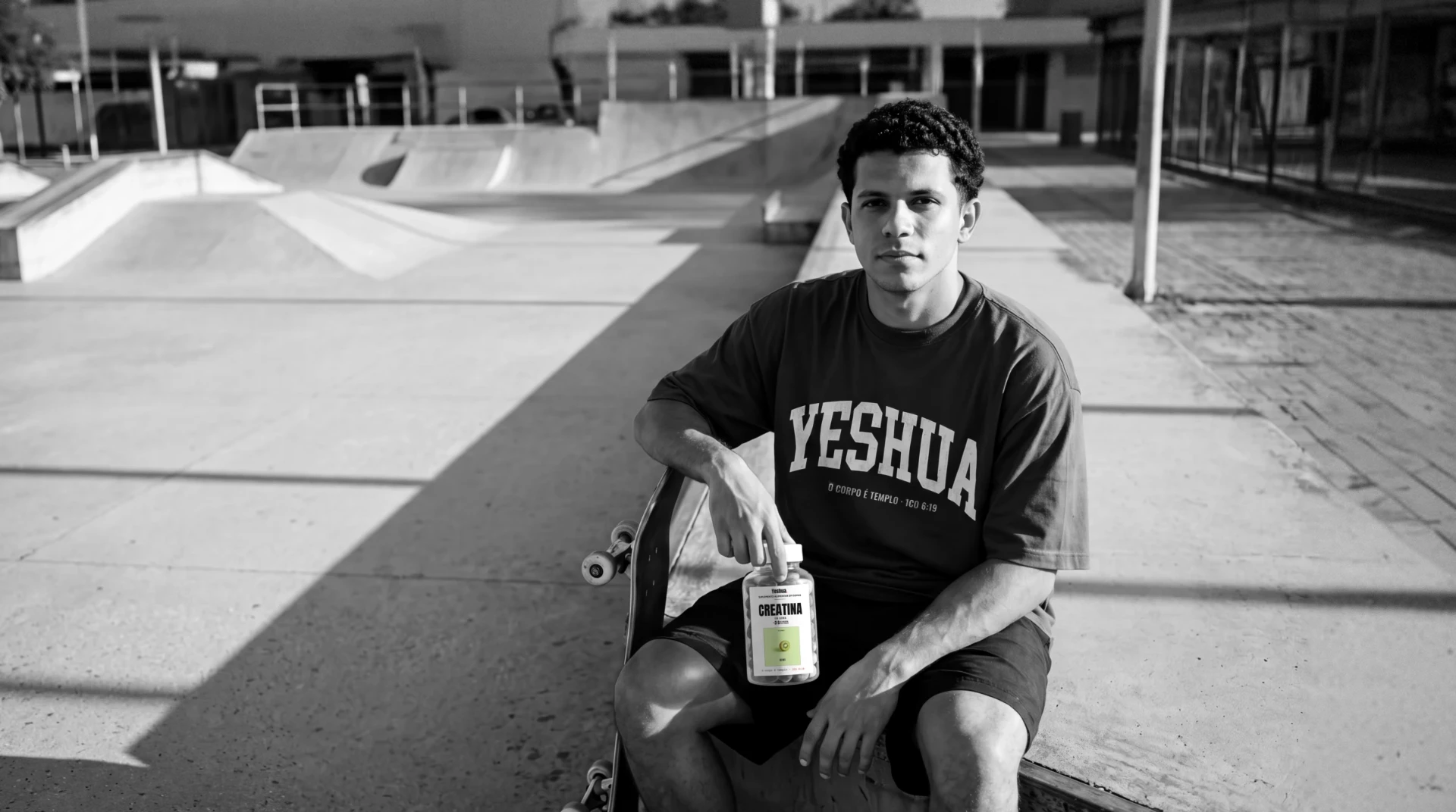 Davi, 20, na pista de skate com a camiseta Atlética azul royal e o pote de creatina em goma sabor kiwi