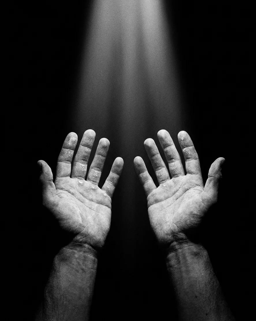 Duas mãos abertas, viradas para cima, sob um feixe de luz