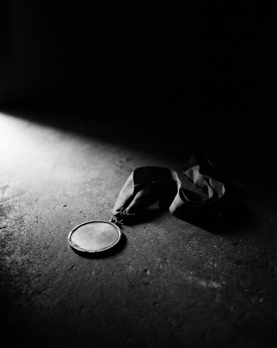 Uma medalha esquecida no chão, no escuro